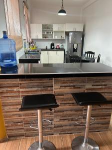eine Küche mit zwei Barhockern vor einer Theke in der Unterkunft Alojamiento en departamento compartido in Cajamarca