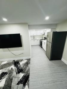 a kitchen with a refrigerator and a tv on a wall at C&M Beautiful Basement in Brampton