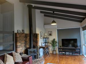 a living room with a brick fireplace and a tv at Littlehurst Lodge in Millgrove