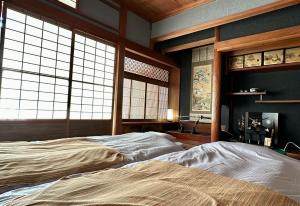 una camera con un letto in una stanza con finestre di Guest House 古民家 NAGOMI a Izumisano