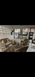 a living room with a couch and chairs and windows at La casa de Maria in Santo Domingo