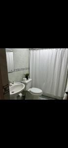 a bathroom with a white toilet and a sink at La casa de Maria in Santo Domingo