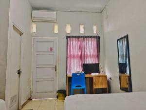 - une chambre avec un lit, une chaise bleue et un bureau dans l'établissement oemah jawa guesthouse jember, à Jember