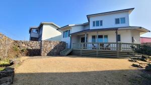a large white house with a stone retaining wall at Haumok52 Udo in Jeju