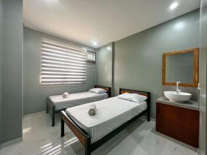 een slaapkamer met 2 bedden, een wastafel en een spiegel bij Monati Hostel Panglao in Panglao