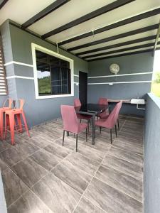 une terrasse avec des chaises roses et une table noire dans l'établissement Perry Barr La Ganta Residence, à Temerloh