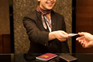 un homme en costume portant à une personne un morceau de papier dans l'établissement Sheraton Brussels Airport Hotel, à Zaventem