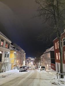 uma rua da cidade à noite com neve no chão em Cozy 2bdr apt. 3 min walk to Solsiden em Trondheim