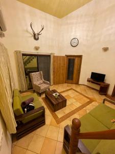 ein Wohnzimmer mit einem Sofa, einem Tisch und einer Uhr in der Unterkunft The Colonial Kaanchi House Mount Abu in Mount Ābu