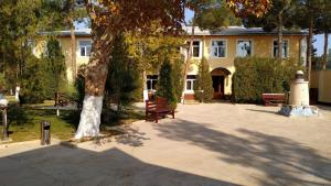 a building with a tree and benches in front of it at ADMIRAL in Termiz