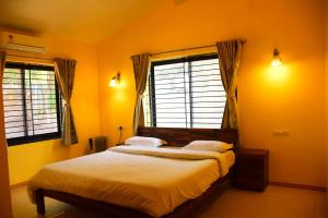 Schlafzimmer mit einem Bett mit gelben Wänden und Fenstern in der Unterkunft The Colonial Kaanchi House Mount Abu in Mount Ābu