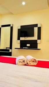 - une chambre avec 2 serviettes sur un lit et une télévision dans l'établissement Neo Himalyan stays, à Dharamshala