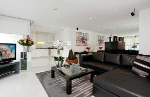 a living room with a black leather couch and a tv at BYD Lofts - Boutique Hotel & Serviced Apartments - Patong Beach, Phuket in Patong Beach