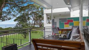 a porch with a bench and chairs on a balcony at Beachfront- The Art Cottage- Pet Friendly in Vincentia