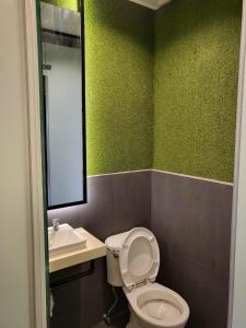 baño con paredes verdes, aseo y lavamanos en Ramos Hello Stay Cebu, en Cebú