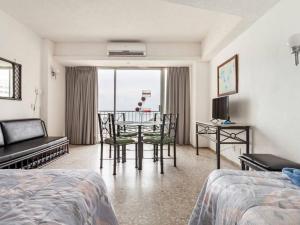 ein Hotelzimmer mit einem Bett, einem Tisch und Stühlen in der Unterkunft Suite 1808 by Suites Victoria Acapulco in Acapulco