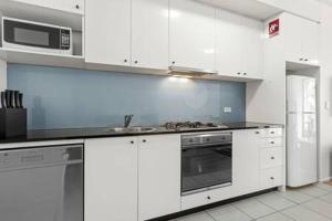 a kitchen with white cabinets and a stove top oven at A Comfy Studio for 5 Next to Darling Harbour in Sydney +16 photos