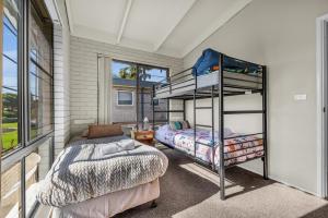 a bedroom with two bunk beds and a window at Admirals Lodge in Merimbula