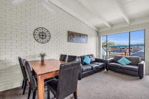 a dining room with a table and chairs and a couch at Admirals Lodge in Merimbula
