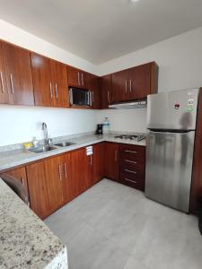 een keuken met houten kasten en een roestvrijstalen koelkast bij ¡Departamento a 5 minutos del Malecón! in Mazatlán