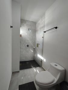 uma casa de banho branca com um chuveiro e um WC. em ¡Departamento a 5 minutos del Malecón! em Mazatlán