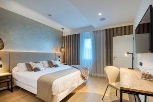 Habitación de hotel con cama, mesa y escritorio. en Hotel Costabella, en Girona 37 fotos más