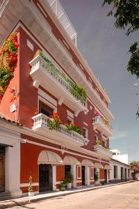 Basilica Hotel في سانتا مارتا: مبنى احمر وبيض مع ورود على البلكونات