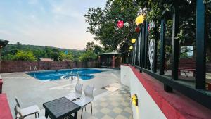 a swimming pool with chairs and a table and a bench at SHARDUL HERITAGE THE RESORT in Mahabaleshwar