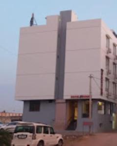 um edifício branco com carros estacionados em frente em Hotel Krish , Somnath em Somnath