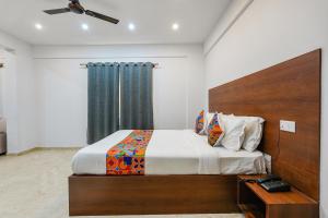 a bedroom with a bed with a wooden headboard at FabHotel Tree Suites in Bangalore
