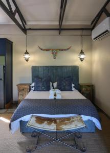 a bedroom with a large bed with blue pillows at Grace of Africa, Couples 5 STAR Nature Lodge in Marloth Park
