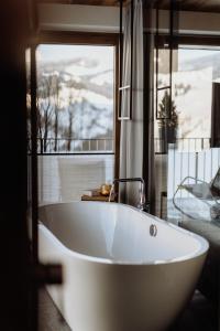 a white bath tub in a bathroom with a window at Biohof Ebengut in Maria Alm am Steinernen Meer +203 photos