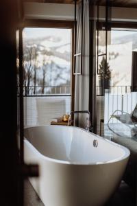 a white bath tub in a bathroom with a window at Biohof Ebengut in Maria Alm am Steinernen Meer