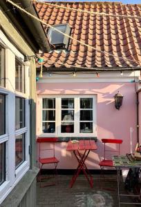 ein rosafarbenes Haus mit roten Stühlen und einem Tisch in der Unterkunft Skønt fiskerhus. Tæt på by, havn og havet in Marstal