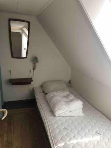 uma cama branca num quarto com um espelho em Skønt fiskerhus. Tæt på by, havn og havet em Marstal