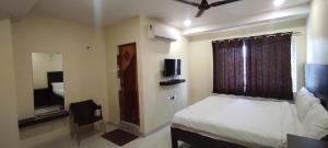 a bedroom with a bed and a window with a television at Arvind Stay Hotel, RK Beach Vizag in Visakhapatnam