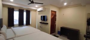 a small bedroom with a bed and a tv at Arvind Stay Hotel, RK Beach Vizag in Visakhapatnam