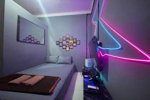 een kleine kamer met een bed en een neonlicht bij Treebox in Ngadipuro