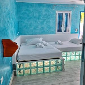 two beds in a room with blue walls at Suite House L'Isola Che Non C'è in Fontane Bianche