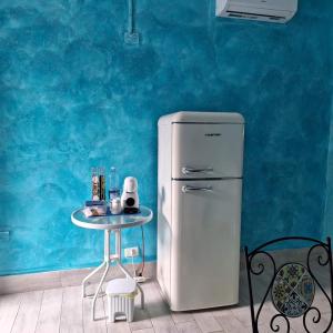a refrigerator and a table in a room with a blue wall at Suite House L'Isola Che Non C'è in Fontane Bianche