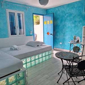 1 dormitorio con 2 camas, mesa y puerta en Suite House L'Isola Che Non C'è, en Fontane Bianche