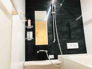 a bathroom with a shower with a mirror and a sink at アンドステイ島尻5丁目 in Tokyo
