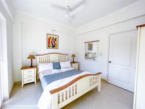 a white bedroom with a bed and two night stands at B&F Meadows - Your Premier Apartment Hotel in Revora
