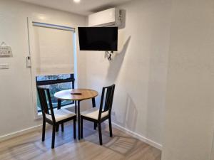 a dining room table and two chairs with a tv on the wall at Cosy Secure comfortable for two in Canberra in Hall