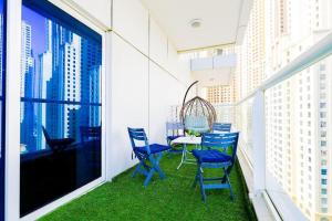 uma varanda com cadeiras azuis, uma mesa e uma janela em 1BR Luxury Apartment close to JBR Beach Marina em Dubai