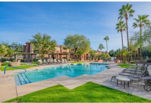 a swimming pool in a resort with chairs and palm trees at Modern 2BR-2BA Condo Pool, Gym & Parking Near Airport in Phoenix