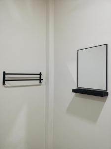 a white wall with a mirror and a black shelf at Villa Tok Wan in Kuantan