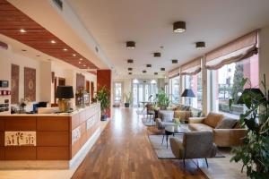 an office lobby with couches and tables and windows at Charme Hotel in Prato