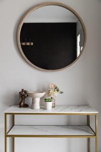 un espejo en una pared blanca sobre un estante con flores en Modern 4BR house perfect for family getaway, en Point Cook