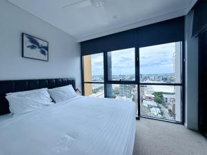 a bedroom with a white bed and a large window at Urban Riverside Escape at Cultural Centre Precinct in Brisbane